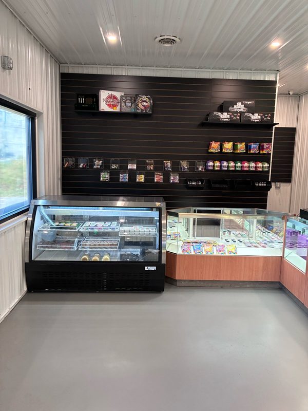 Side room at WeedMart with a refrigerated display case, glass counters and a slat wall display