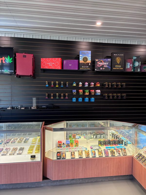 Shelves on a black slat wall above glass display cases at WeedMart in Irving, NY
